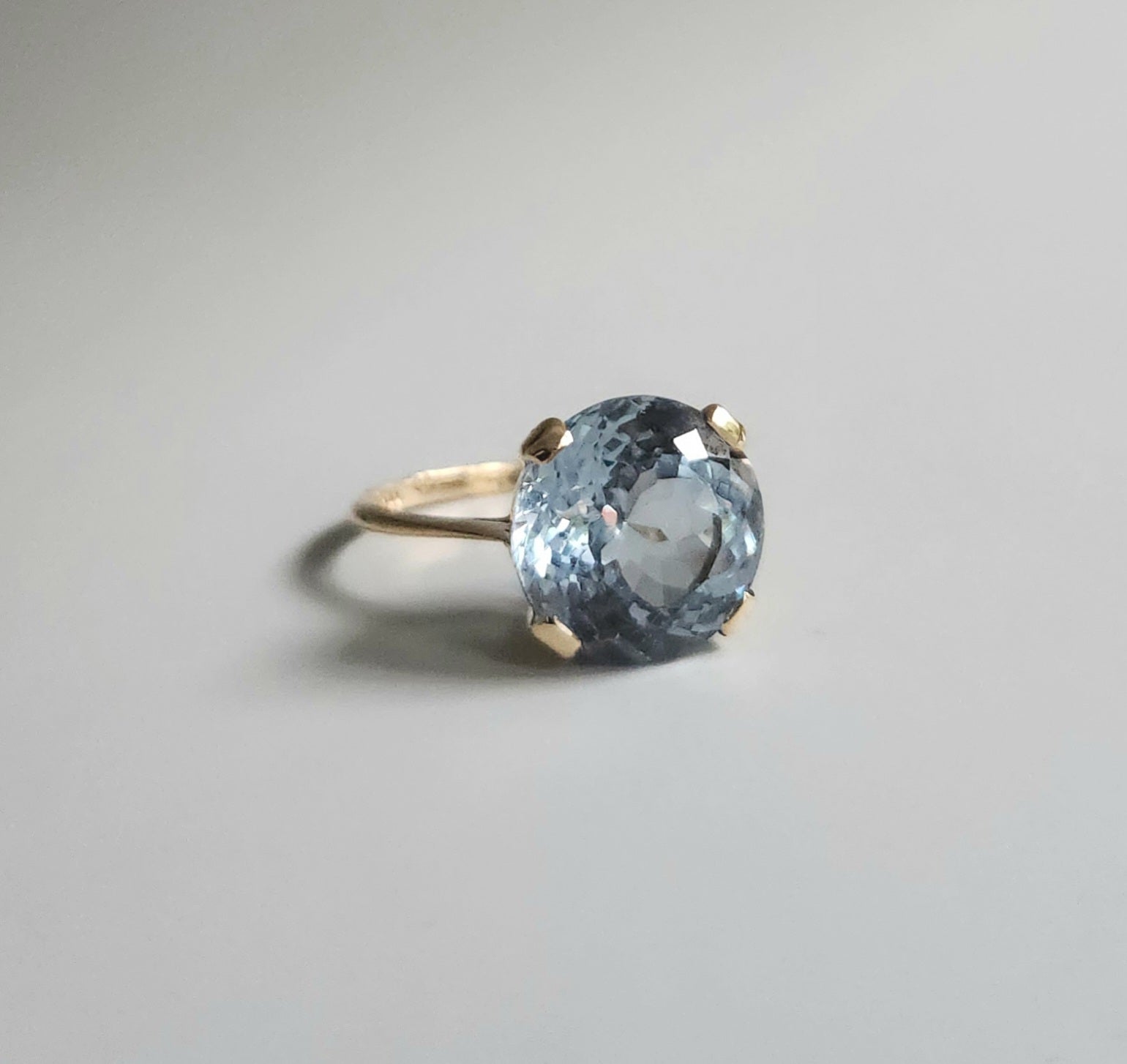 Gold ring with a large blue gemstone on a light gray background